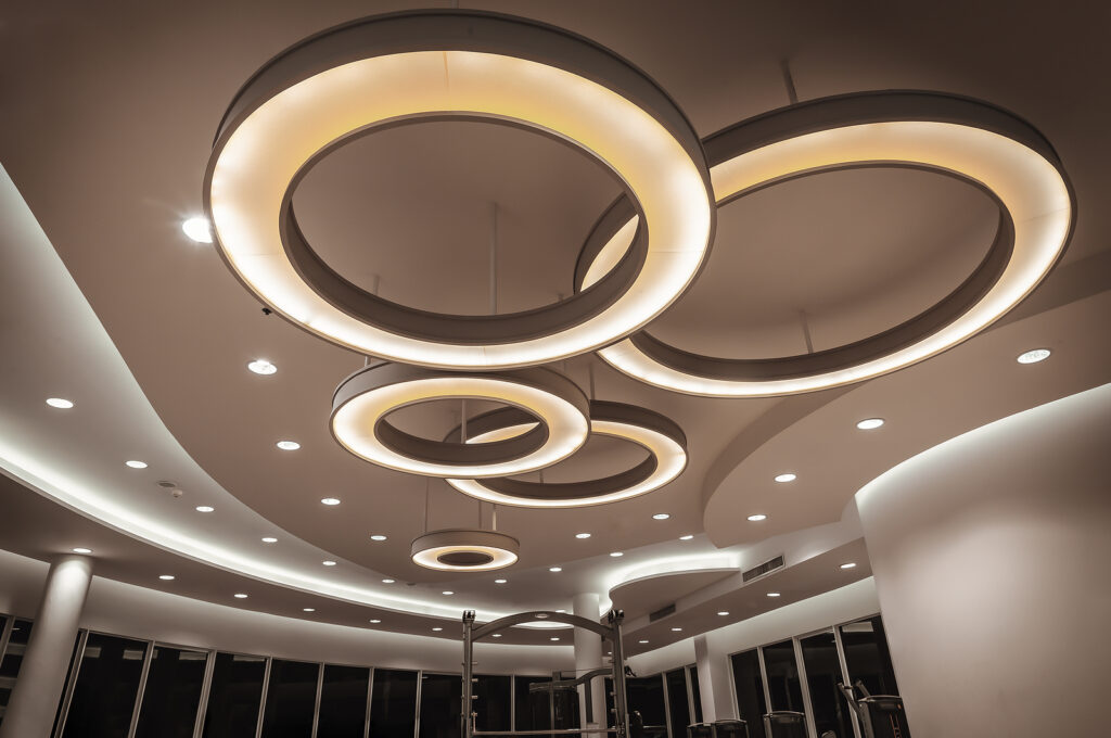 Hanging rounded ceiling mounted light fixtures with modern LED light bulb. Yellow circular ring shaped lamps hang under ceiling, Architecture and interior design round lights on ceiling. Space for text, Selective focus.